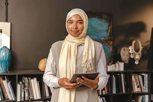 Mujer con hijab y tableta en biblioteca