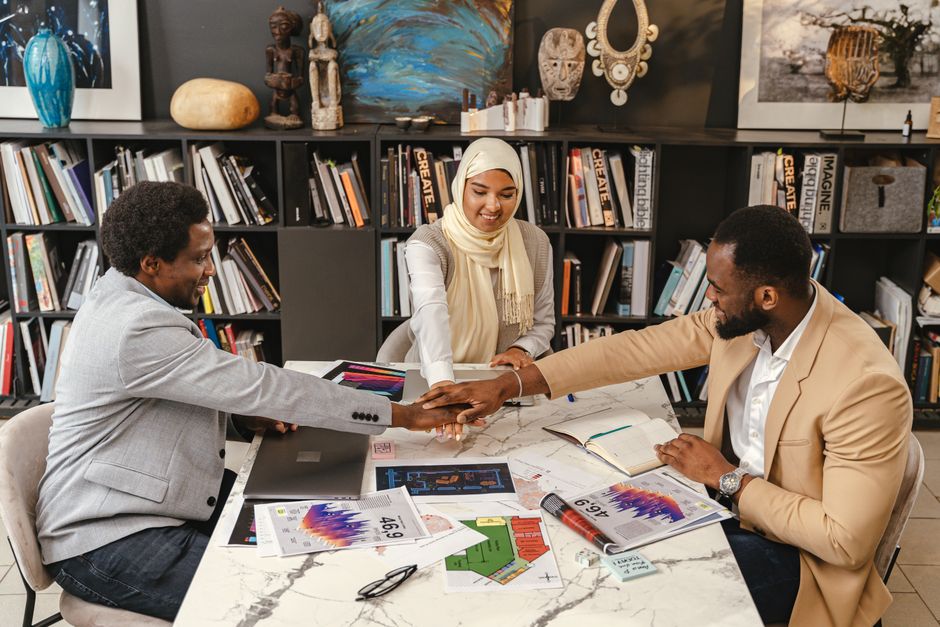 Three professionals in an office setting engage in team collaboration, fostering innovation and cooperation.