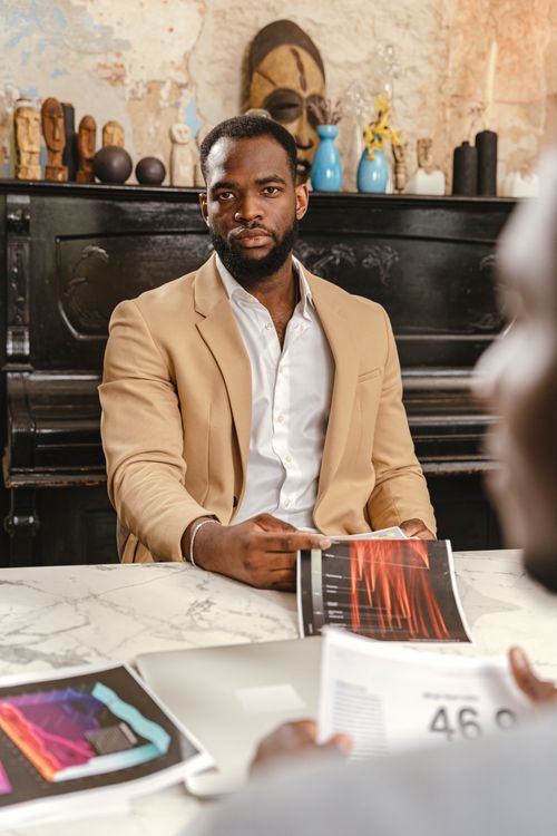 Free Confident professional in a brown blazer leading a meeting at the office table. Stock Photo