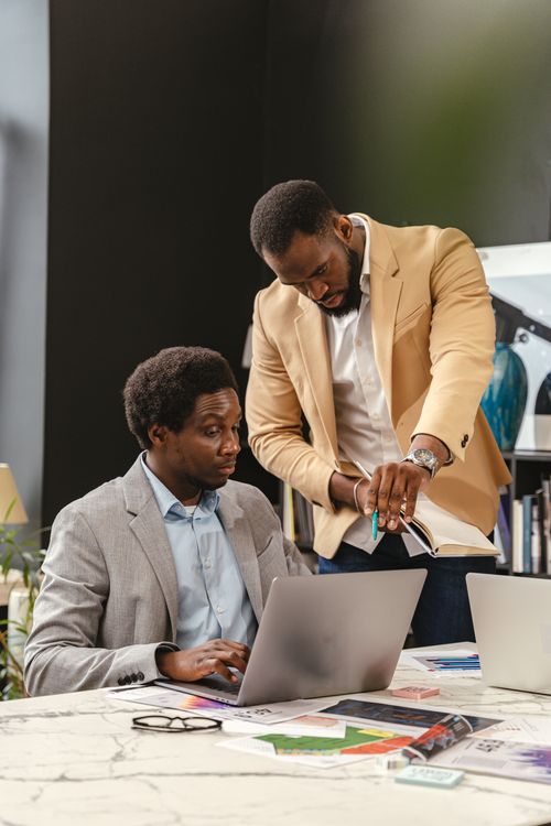 Free Two business professionals working together in an office space with laptops and papers. Stock Photo