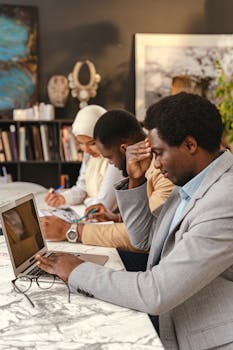 A diverse team working together in a modern office, seated at a marble table with a laptop.