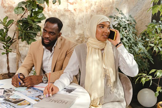 Two colleagues busy at work in a stylish office setting with plants.