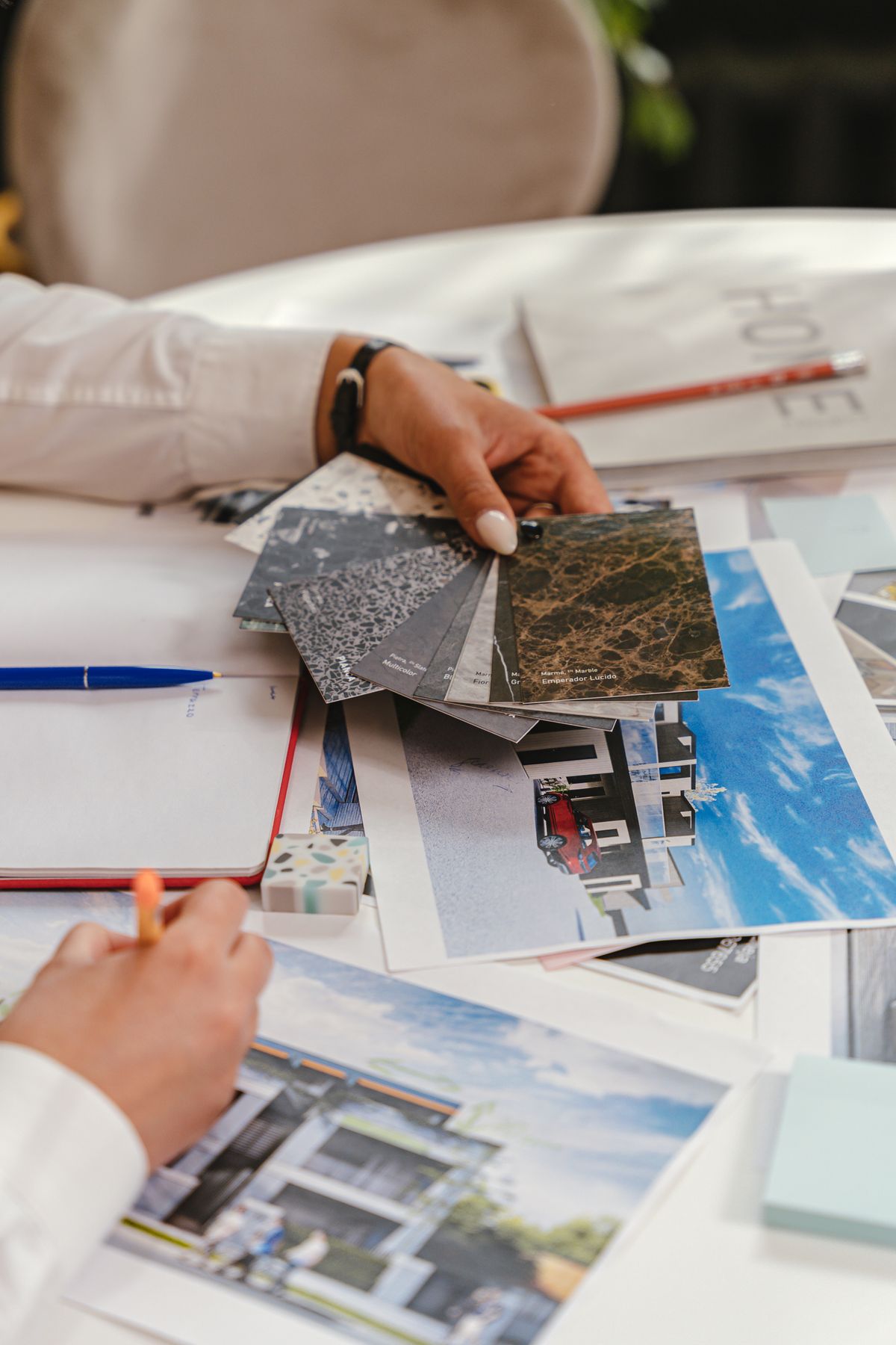 An architect comparing stone material samples beside printed building designs