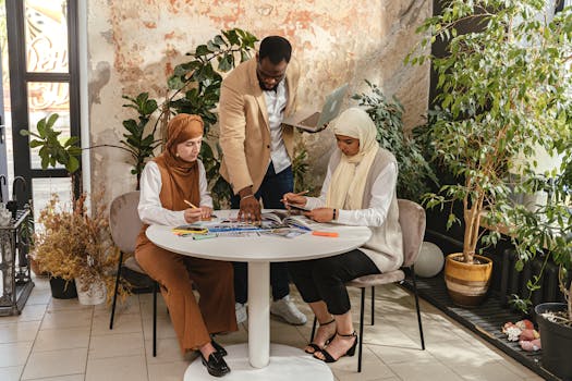 A diverse group of professionals collaborating around a table in a modern office setting with natural elements.