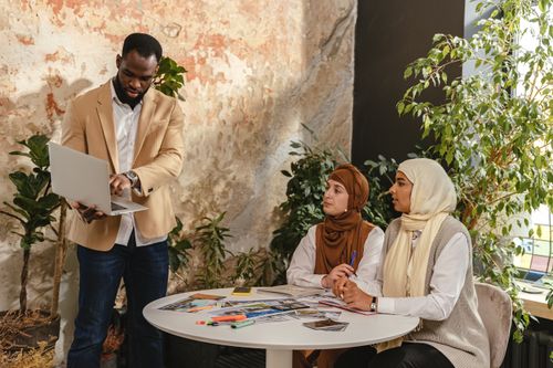 Free Professional business team in meeting with laptops, papers, and diverse attire, collaborating indoors. Stock Photo