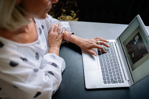 An adult using a laptop in a office space, focused on work. Polka dot attire indicates a casual style.