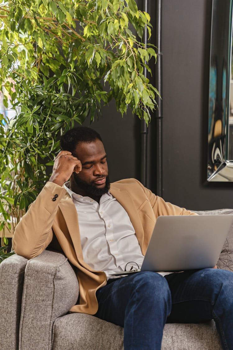 Bored Man Falling Asleep On Couch With Laptop