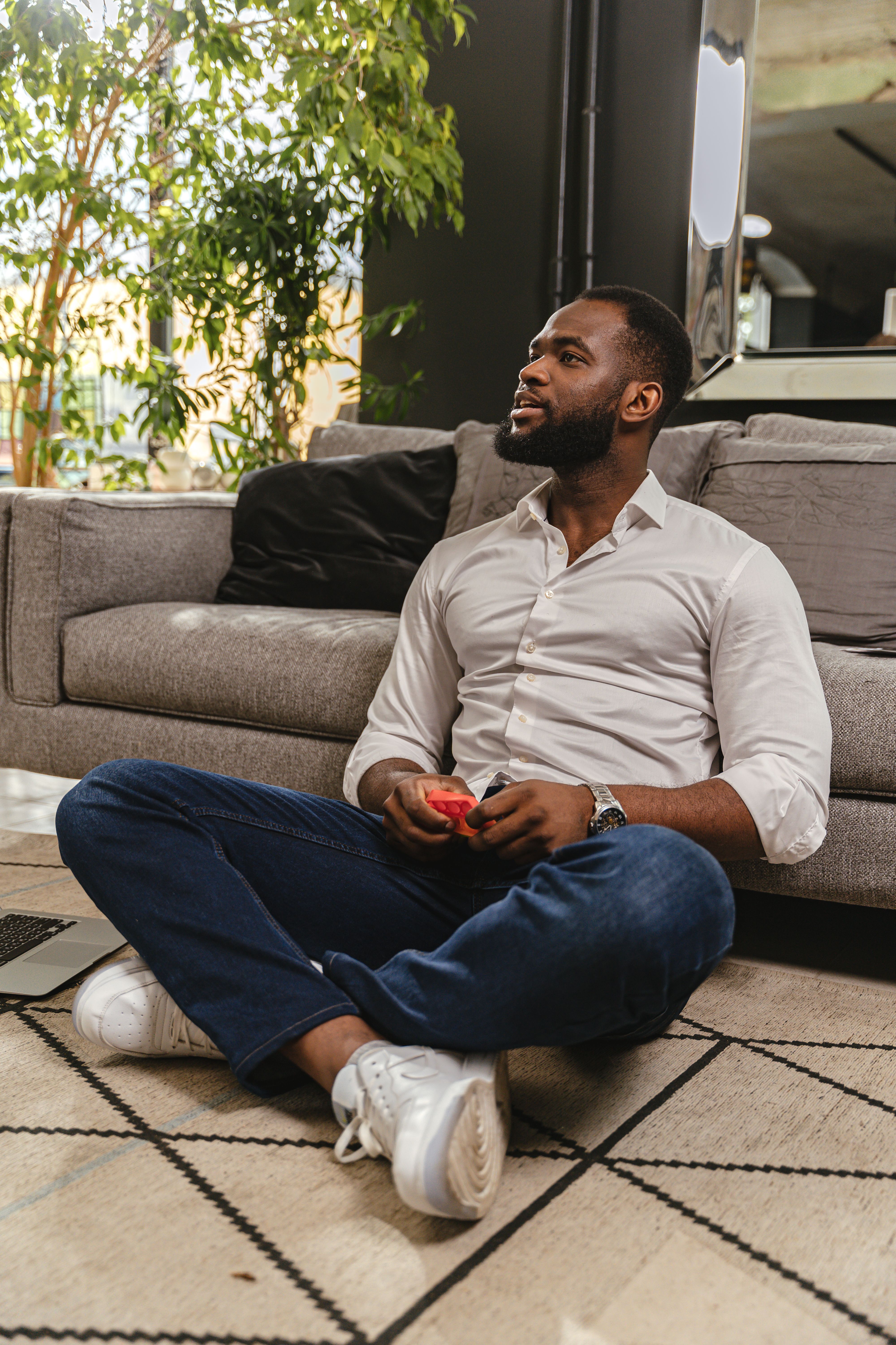 Man Sitting on Carpet and Leaning against Sofa · Free Stock Photo