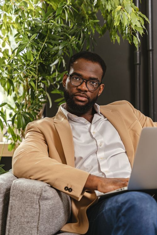 Free Confident man in glasses using laptop in a stylish indoor setting. Stock Photo