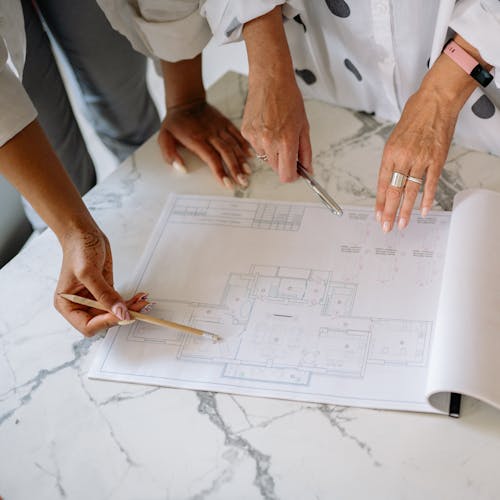 Women Pointing at Blueprint of House