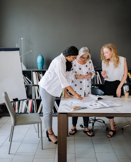 Women in the Meeting Room Looking at the Book on the Table