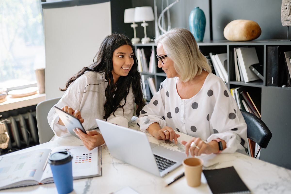 Two business professionals working together with a laptop and tablet in a modern office