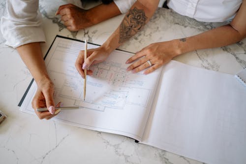 Free People Looking at the Floor Plan on the Marble Top Table Stock Photo