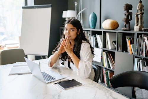 A Woman Sitting at Her Work Desk with a Laptop and Digital Tablet