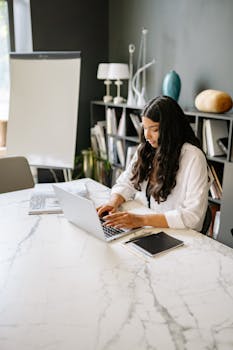 Businesswoman working on a laptop at a modern office desk. Ideal for workplace and productivity themes.