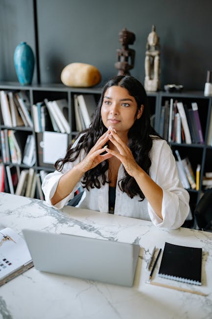 Portrait of a woman thinking at a marble desk with a laptop and decor background.