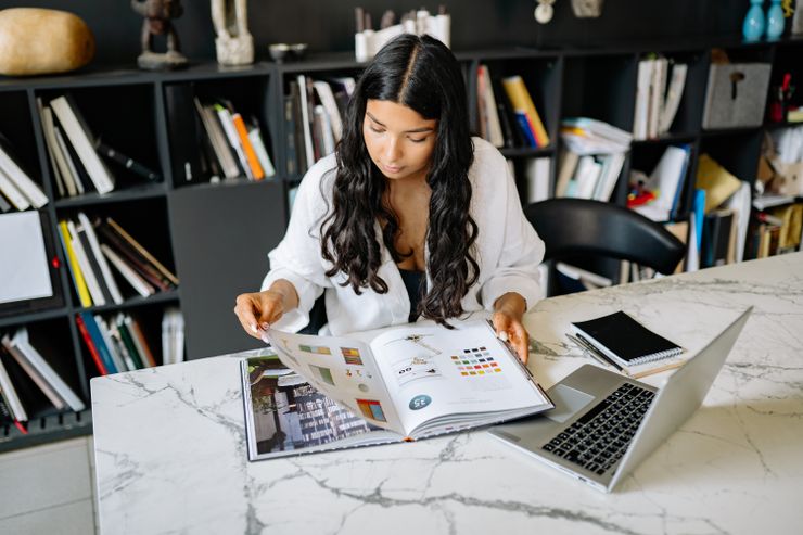 A writer at a desk with a book open in front of shelves — photo by Yan Krukau on Pexels