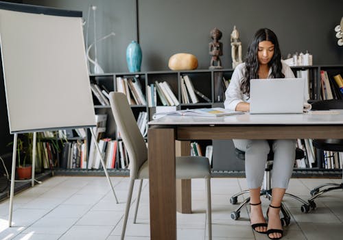 A Woman Sitting while Working on Her Laptop