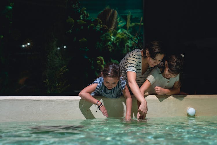 Two Girls And A Woman Playing With Water In A Pool