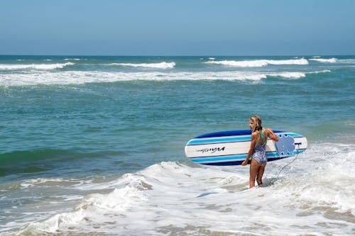 Woman Holding a Surfboard on the Beach