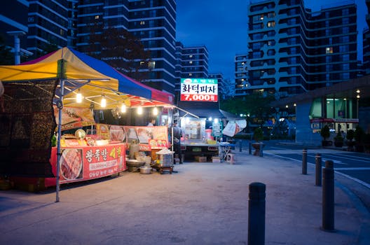 Outdoor street food stall at night in urban cityscape with modern buildings.