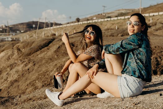 Two women relaxing in the sun with sunglasses, enjoying a scenic outdoor moment.