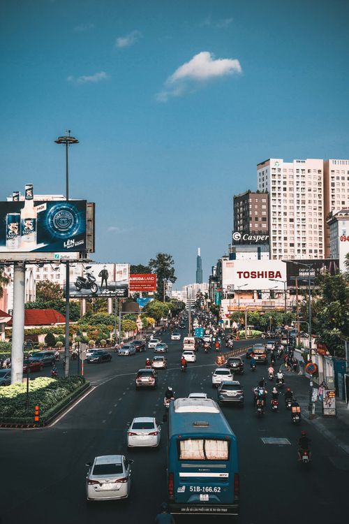 Free Dynamic view of traffic and urban landscape in Ho Chi Minh City, featuring vehicles and billboards. Stock Photo