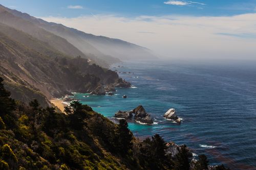 Free Explore the breathtaking landscape of rugged cliffs and clear blue ocean in this fog-kissed coastal scene. Stock Photo