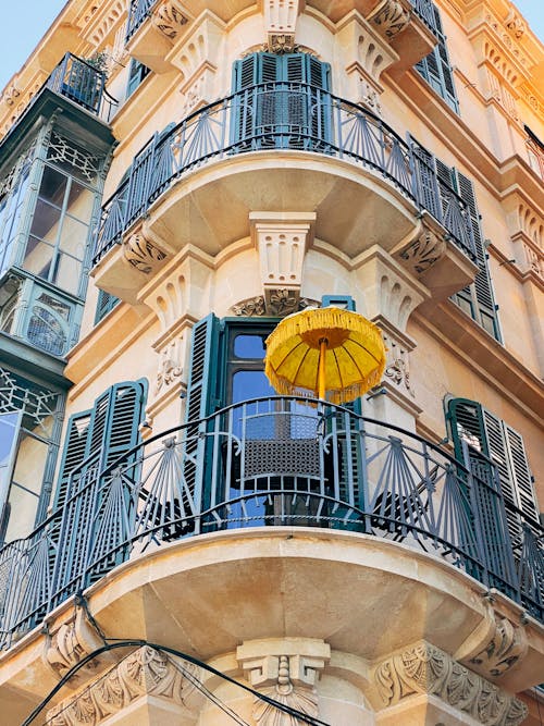 Free Corner of residential building with metal fences on balconies and yellow umbrella in classic style located on street in city Stock Photo