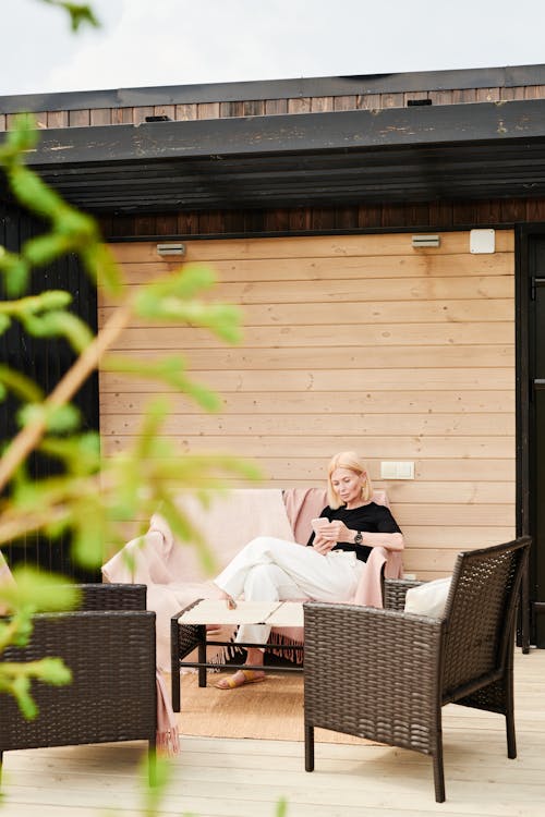 Woman Sitting on Chair in the Patio Using Cellphone