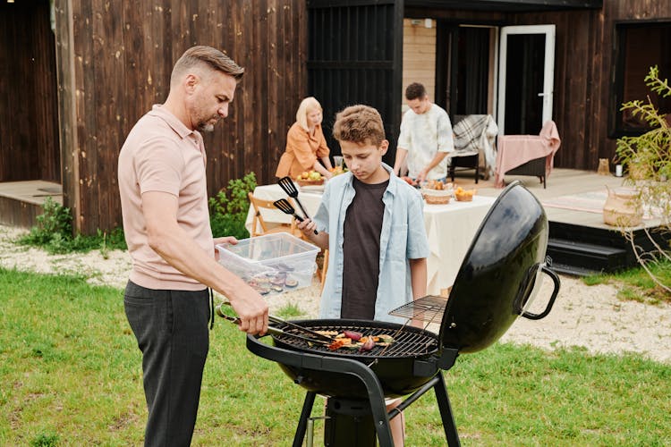 Man And A Boy Grilling Food