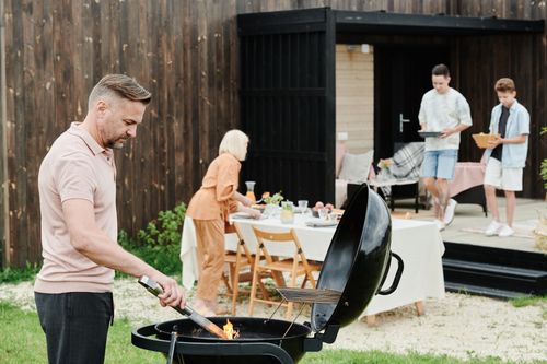 Free A happy family enjoys an outdoor barbecue in their backyard, fostering togetherness. Stock Photo