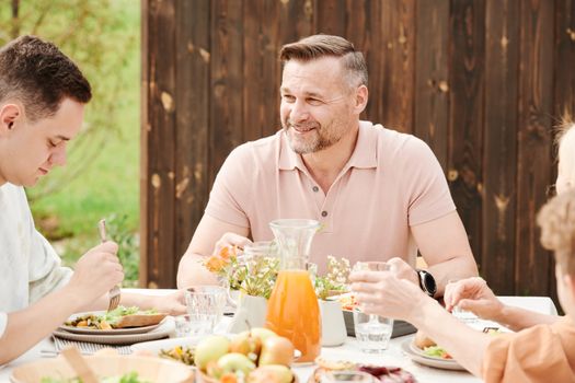 A cheerful family enjoying an outdoor meal together in a warm setting.