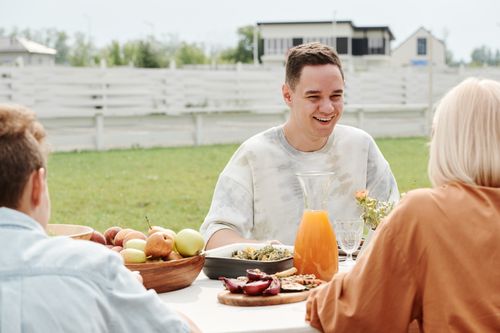 Free A happy family sharing a joyful meal outdoors, filled with smiles and laughter. Stock Photo