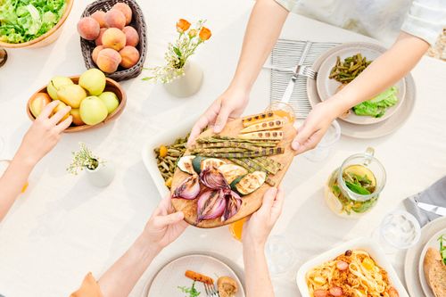 Free Overhead view of a family sharing a meal with fresh grilled vegetables and fruits, perfect for a healthy lifestyle. Stock Photo