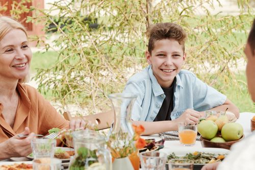 Free Smiling family of four dining outdoors, capturing moments of togetherness. Stock Photo