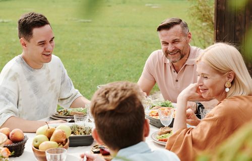 Free A cheerful family enjoying a meal together outdoors, sharing laughter and warmth. Stock Photo