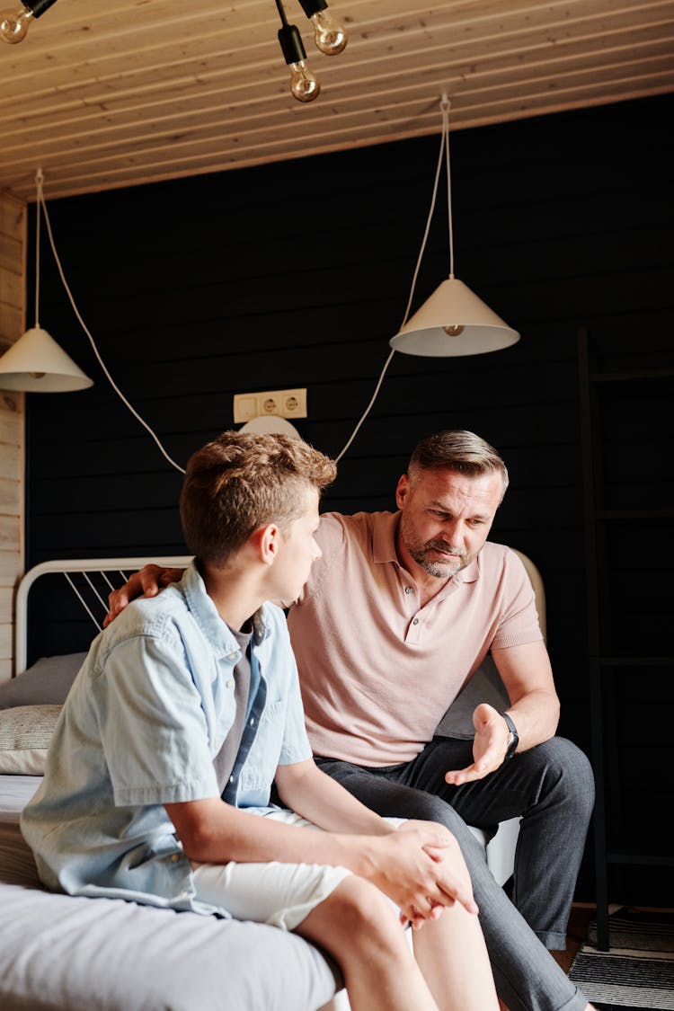 Father And Son Talking In Bedroom