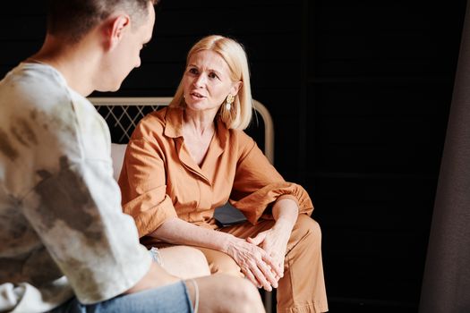 A candid moment of a mother and adult son having a heartfelt conversation indoors.