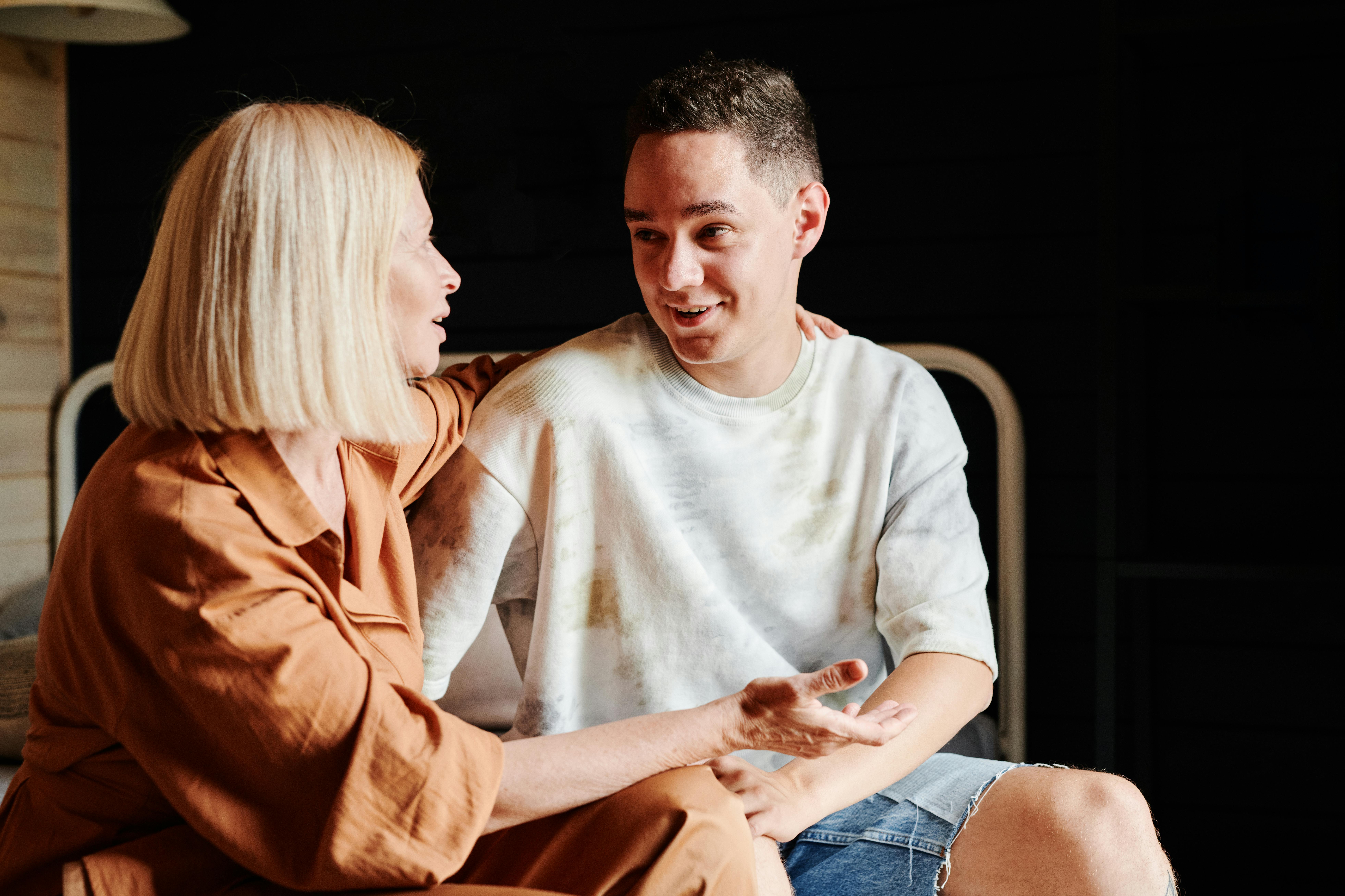 Free Woman Talking to Her Son While Sitting Beside Him Stock Photo