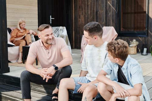 Free Family sharing quality time on a wooden terrace. Smiling and conversing. Stock Photo