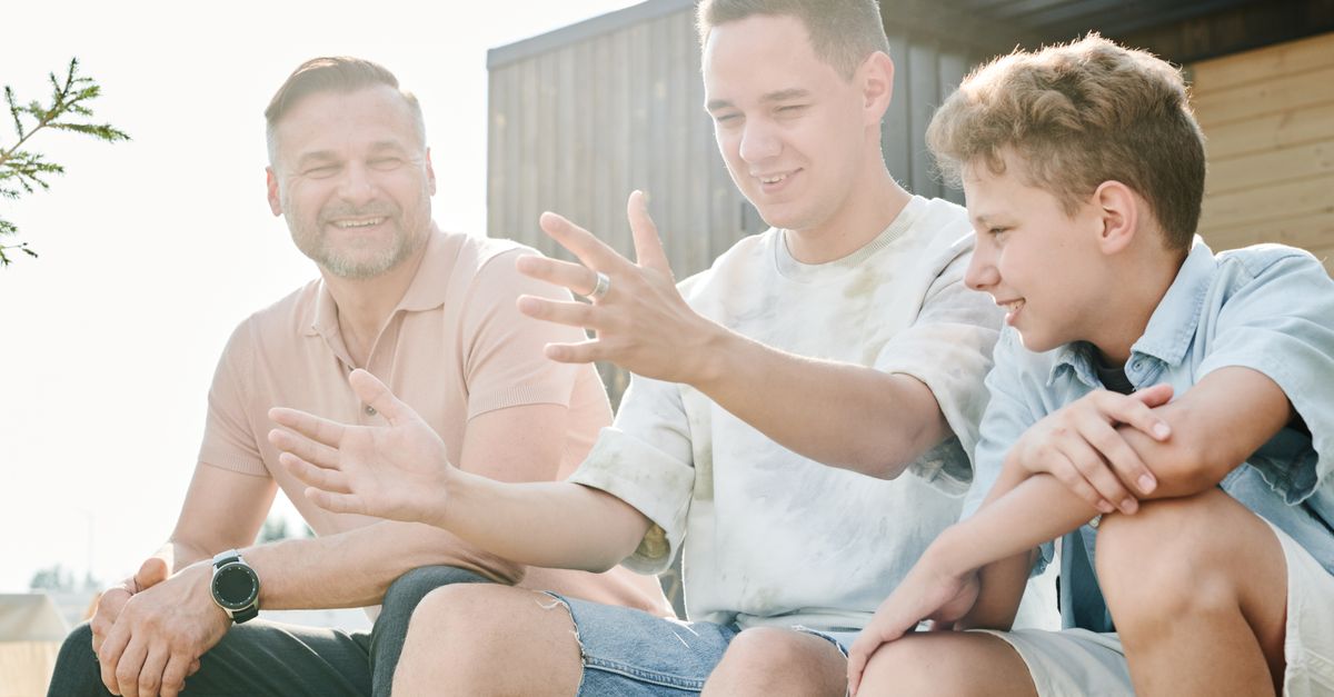 A father and his two sons sharing a joyful moment outdoors, symbolizing family bonding and togetherness.