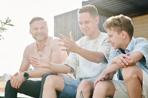 Free A father and his two sons sharing a joyful moment outdoors, symbolizing family bonding and togetherness. Stock Photo