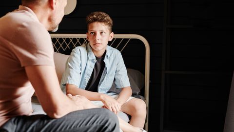 A father and son share a heartfelt conversation indoors, capturing a moment of bonding.