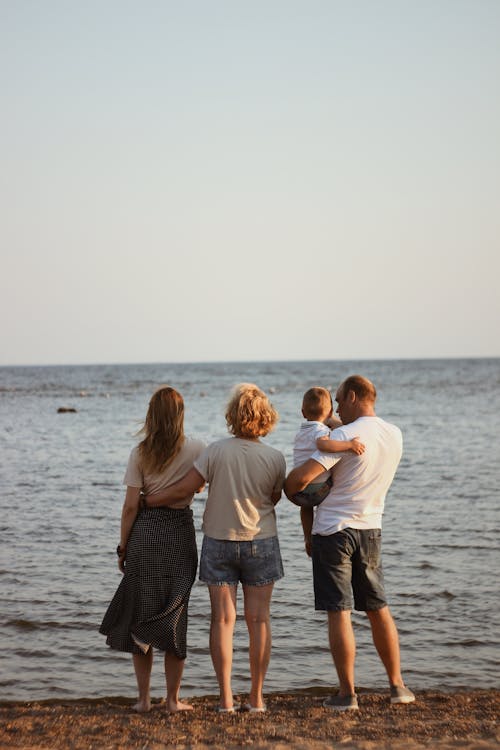 Back View of a Family Together at the Beach Looking at the Sea 