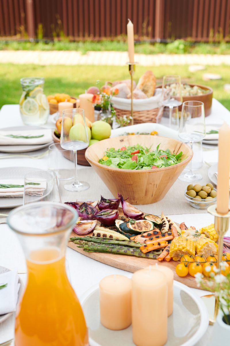 Platters of grilled vegetables and roasted peppers on an outdoor table in a garden