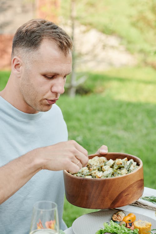 Man in Gray Crew Neck T-shirt Holding a Brown Wooden Bowl With Food