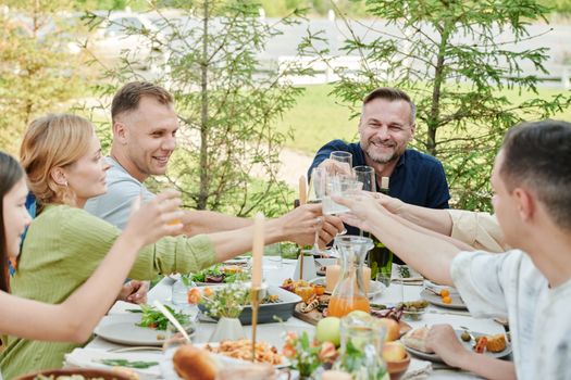 Happy group of friends enjoying an outdoor dinner with a toast.