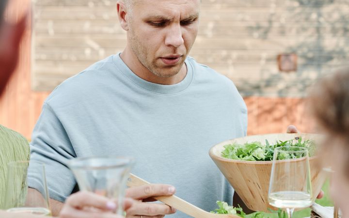 Man enjoying a healthy salad and orange juice at an outdoor meal. Perfect summer vibes.