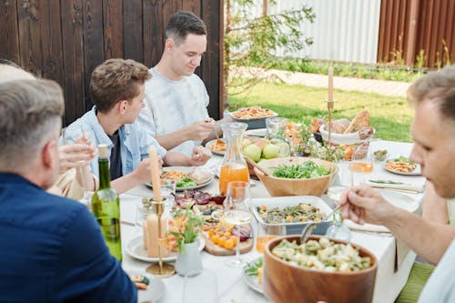 Free Man in White Crew Neck T-shirt Sitting on Chair in Front of Table With Food Stock Photo